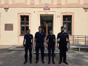 policjantka i trzech policjantów w mundurach przed budynkiem komendy