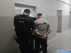 policjant prowadzi zatrzymanego korytarzem