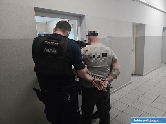 policjant prowadzi zatrzymanego korytarzem
