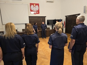 Komendant przemawia, zwraca się bezpośrednio do stojącej obok policjantki