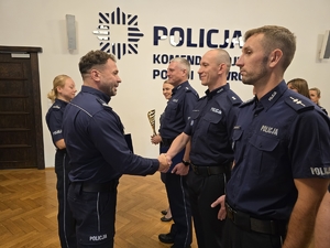 Komendant podaje rękę policjantowi, w tle stoją pozostali wyróżnieni policjanci