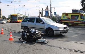 zgnieciony motocykl na środku drogi obok samochód osobowy
