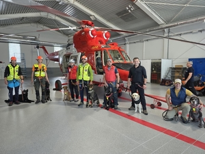 funkcjonariusze różnych służb z psami w hangarze lotniczym obok helikoptera ratunkowy