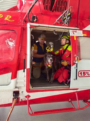 dwaj funkcjonariusze służb ratunkowych z psem w helikopterze