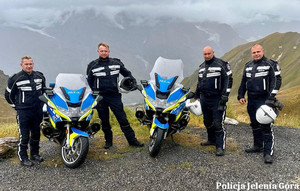 Czterech policjantów w górach obok dwa policyjne motory
