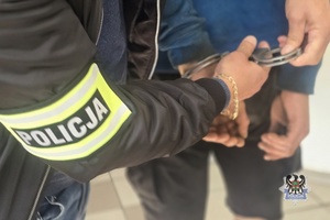 policjant zakłada kajdanki na ręce zatryzmanego