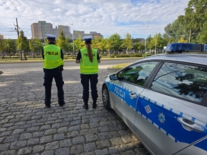 policjantka i policjant przy radiowozie stoją na poboczu