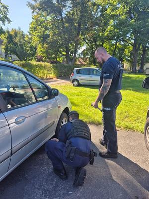 policjanci pomagają zmienić koło w samochodzie