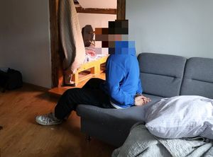 mężczyzna w kajdankach siedzący na łóżku