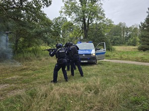 policjanci w pełnym umundurowaniu ćwiczebnym w szyku bojowym oddają strzały z broni palnej
