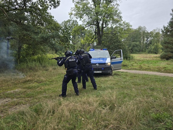 policjanci w pełnym umundurowaniu ćwiczebnym w szyku bojowym oddają strzały z broni palnej