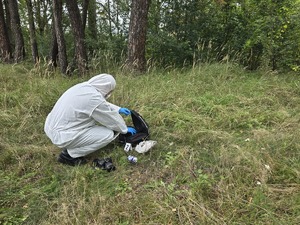 policjant w ubraniu laboratoryjnym otwiera teczkę