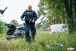 policjant biegnie po przedmiot leżący w trawie