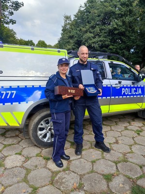 policjantka i policjant z trofeami po biegu weterana przy radiowozie