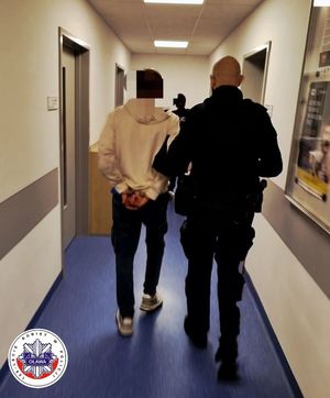 policjant prowadzi zatrzymanego skutego w kajdanki
