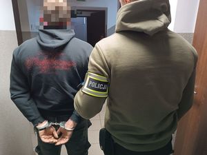 policjant prowadzi zatrzymanego w kajdankach na rękach