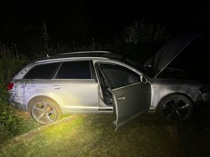 uszkodzone srebrne audi po zderzeniu z ogrodzeniem z otwartymi drzwiami