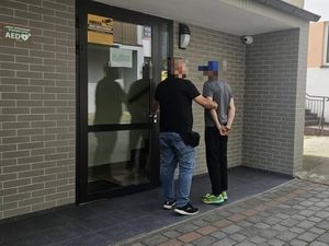 policjant prowadzi zatrzymanego skutego w kajdanki