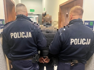 dwóch policjantów prowadzi zatryzmanego