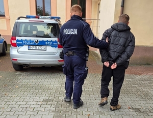policjant prowadzi zatrzymanego do radiowozu