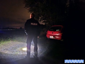 Policjant w porze nocnej koło samochodu osobowego