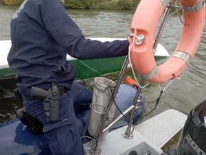 policjanci na łódce ratują tonącego męzżyzne