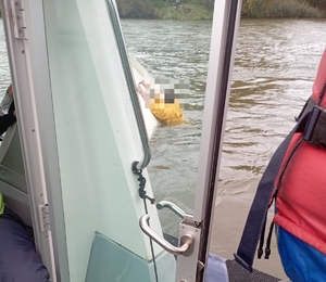 policjanci na łódce ratują tonącego męzżyzne