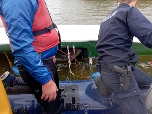 policjanci na łódce ratują tonącego męzżyzne