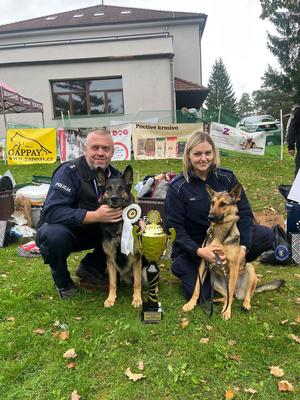 policjantka z psem i policjant z psem wraz z pucharami i medalami