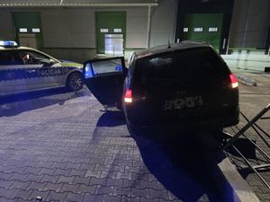 samochód osobowy po zderzeniu z ogrodzeniem obok radiowóz