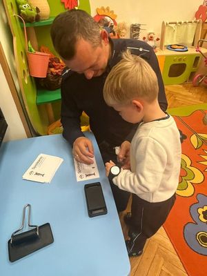 policjant pokazuje chłopcu jak pobierane są odciski palców