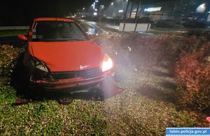 czerwony samochód osobowy z rozbitym przednim światłem wjechał na rondo