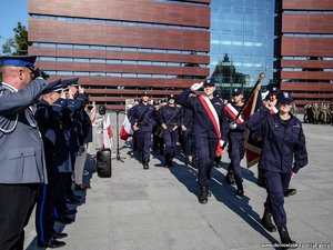 Na zdjęciu widocznie są młodzi ludzie w granatowych mundurach idący grupą na placu