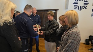policjant wręcza puchar młodemu mężczyźnie obok stoją dwie kobiety