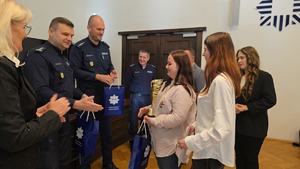 zastępca komendanta wojewódzkiego policji wręcza torbę z prezentami młodej kobiecie