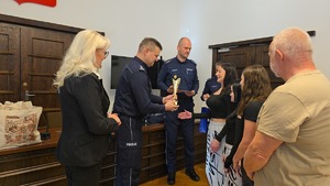 zastępca komendanta wojewódzkiego policji wręcza puchar młodej kobiecie
