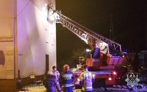 strażacy na wysięgniku wozu strażackiego wchodzą do pomieszczenia