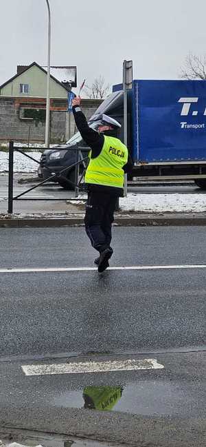 policjant wychodzi na ulicę i zatrzymuje pojazd