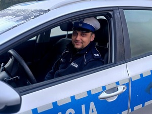 uśmiechnięty policjant siedzący w radiowozie
