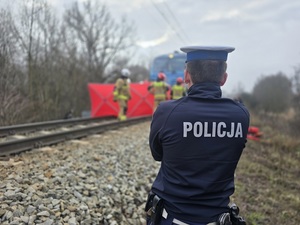 policjanci w oznakowanych mundurach stoją przy torach kolejowych