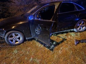 samochód osobowy na poboczu z otwartymi drzwiami od strony kierowcy, obok leżący na ziemi zatrzymany