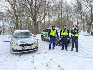 trzej policjanci obok radiowozów na śniegu