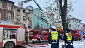 pożar budynku obok którego stoją służby w tym także straż pożarna