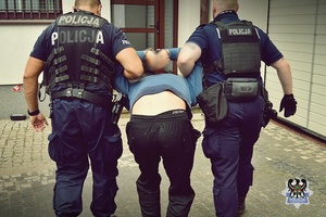 dwaj policjanci prowadzą zatrzymanego