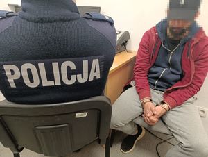 policjant przesłuchuje zatrzymanego, skutego w kajdanki mężczyznę