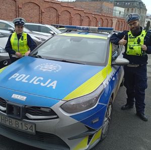 policjantka i policjant stoją obok radiowozu