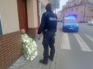 policjant z mężczyzną przykrytym kocem ratunkowym