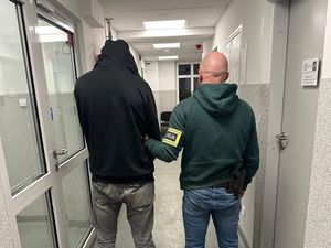 policjant prowadzi zatrzymanego