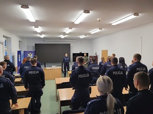 policjanci podczas zajeć w szkole siedzą w ławkach i stoja na apelu