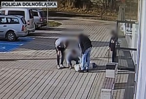 mężczyzni pomagają kobiecie leżacej na chodniku